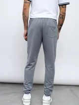 Pantalón de jogging gris de felpa sin friza, con cintura elástica ajustable con cordón y logo de Umbro estampado en blanco en el muslo izquierdo.
