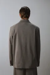 Blazer de corte relajado en color marrón oscuro, con cuello de solapas de muesca, cierre frontal de dos botones y bolsillos de plastrón en la parte delantera.