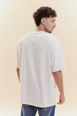 Remera de manga corta color blanco con cuello redondo. Presenta un estampado frontal con la palabra 'URUGUAY' en tipografía universitaria, un sol central en color dorado y la inscripción 'EST 1825'.