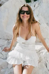Vestido corto de viscosa y algodón, con escote en pico y tirantes finos cruzados en la espalda. Presenta un diseño con pliegues, aplicaciones de lazadas a contraste y falda con volantes en el bajo.