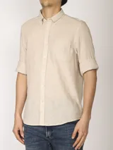 Camisa de manga larga confeccionada en una mezcla de algodón y lino, con cuello abotonado, cierre frontal de botones y un bolsillo en el pecho.