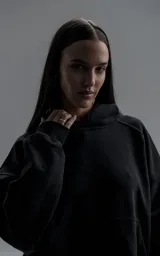 Hoodie oversize de corte crop, color negro, confeccionado en frisa gamuzada de algodón. Presenta capucha forrada, mangas largas con puños elásticos y bolsillo tipo canguro frontal.