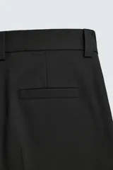 Bermuda negra de corte ancho (wide fit) con pliegues frontales, bolsillos laterales y bolsillos traseros de vivo.