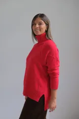 Polerón de punto color rojo con cuello alto y diseño de rombos texturizados. Presenta mangas largas con puños acanalados y un corte holgado con ruedo asimétrico.