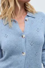 Cardigan de punto color ocre, con diseño calado de pequeños motivos florales, cuello polo y cierre frontal con botones.