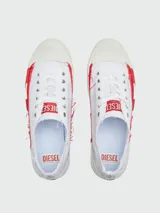 Zapatillas bajas de lona blancas con detalles deshilachados y aplique lateral de goma roja con el logo 'D' de Diesel. Presentan puntera de goma color crema y cordones blancos.