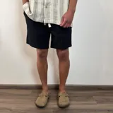 Bermuda de lino color blanco, con cordón ajustable en la cintura y corte arriba de la rodilla.