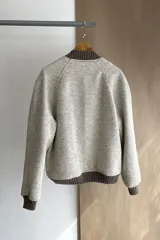 Campera estilo bomber color beige con textura, cierre delantero, cuello, puños y ruedo tejidos. Forrada, confeccionada en lana fina sin teñir.