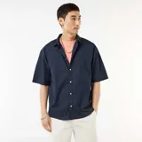 Camisa de manga corta azul marino confeccionada en popelín, con cuello camisero clásico y cierre frontal de botones.