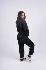 Pantalón de jogging gris oscuro, de corte holgado con cintura elástica y puños ajustados en los tobillos. Presenta bolsillos laterales y un pequeño logo bordado en la pierna izquierda.