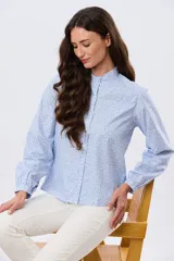 Camisa de algodón celeste con estampado floral pequeño, cuello mao, mangas largas con puños fruncidos y cierre frontal de botones.