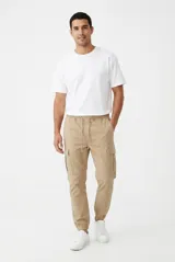 Pantalón jogger cargo color beige, con bolsillos laterales en las piernas, cintura elástica con cordón ajustable y puños en los tobillos.