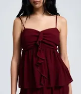 Blusa tipo bata color bordó, confeccionada en crepé, con breteles finos ajustables, busto fruncido y detalle de volado vertical en el frente. Posee espalda con lastex para un mejor ajuste.