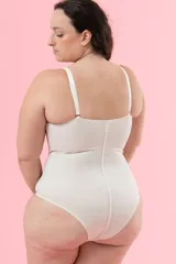 Body modelador blanco con copa y aro, confeccionado en tela de faja de alta contención con refuerzo interno en zona abdominal. Breteles elásticos regulables y ganchos en la entrepierna.