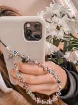 Llavero para celular con cuentas plateadas y dijes de estrella con incrustaciones de colores.