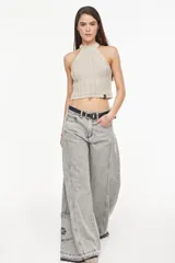 Top de punto estilo halter, color crudo, con cuello alto ajustado, diseño sin mangas y corte corto.