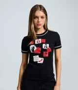 Remera negra de algodón con cuello redondo y mangas cortas con ribete blanco. Presenta un estampado frontal con motivos gráficos inspirados en la película El Diablo Viste a la Moda, incluyendo recortes tipo post-it, ilustraciones y texto.