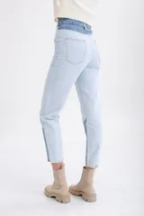 Pantalón de jean celeste con cintura alta y corte recto. Presenta un diseño color block con secciones en denim de tono más oscuro en la cintura y en la parte inferior de las piernas.