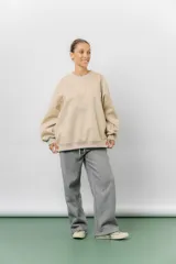 Buzo oversize de algodón frizado color beige, con cuello redondo, puños y cintura tejidos. Presenta un bordado tono sobre tono de Garfield en el frente.