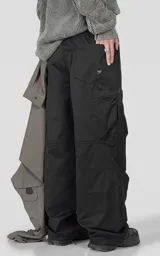 Pantalón cargo de corte regular confeccionado en textil técnico pesado. Presenta cintura elástica con cordón de ajuste, bolsillos laterales en la cintura y bolsillos cargo de gran tamaño en los muslos. Incluye elásticos con tancas en los tobillos para regular la apertura de la pierna.