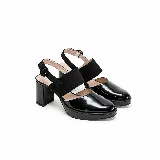 Zapatos de taco alto y plataforma delantera con diseño destalonado. Combinan una puntera cerrada de charol negro con una tira ancha de gamuza sobre el empeine y tira ajustable con hebilla en el talón.