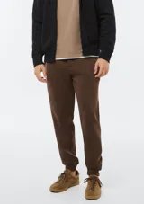 Pantalón babucha deportivo de felpa color gris melange, con cintura elástica ancha, cordones ajustables y puños en los tobillos.