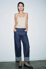 Jeans de tiro bajo color azul oscuro, corte recto, con cinco bolsillos y cierre frontal de cremallera y botón. Presenta un efecto lavado y el bajo está acabado en vuelta.