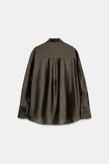 Camisa de corte holgado confeccionada en mezcla de lyocell con acabado satinado. Presenta cuello redondo con lazadas integradas, cierre frontal con botones ocultos bajo solapa, bolsillos de plastrón en el frente y mangas largas con puños anchos. El bajo es asimétrico y redondeado.