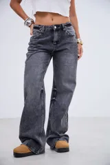 Jean de tiro medio en color negro lavado, con corte recto y amplio. Presenta detalles de tachas metálicas a lo largo de las costuras laterales y en la zona de los bolsillos delanteros.