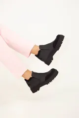 Botín negro de cuero con plataforma track y cierre de cremallera frontal.