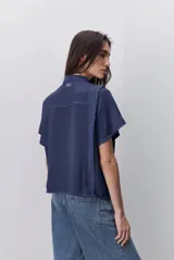 Camisa negra de manga corta, con cuello mao y cierre frontal de botones, de silueta amplia y tejido liviano con textura sutil.