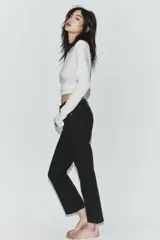 Jeans de tiro alto con diseño cropped flare, confeccionados en denim azul con acabado desgastado. Presentan cinco bolsillos, cierre frontal con cremallera y botón metálico, y bajo con terminación sin costuras.