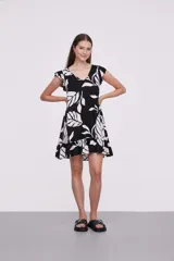 Vestido corto negro con escote en V y mangas cortas con volados. Tiene corte suelto y un volante en el ruedo.