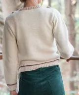 Sweater artesanal tejido a mano en lana merino, de color marfil con detalles en bordó. Presenta cuerpo delantero en crochet con guardas laterales decorativas y espalda en punto jersey, con cuello redondo y puños acanalados en contraste de color.