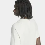 Remera Adidas de corte clásico y cuello redondo, de color blanco. Presenta líneas horizontales oscuras y amarillas en el pecho y el logo del trébol bordado en azul marino.