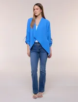 Chaqueta liviana azul de silueta fluida y diseño abierto, con solapa caída, mangas tres cuartos con presilla y argolla metálica, y ruedo irregular.