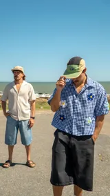 Camisa de corte boxy con estampado de cuadros vichy en azul y blanco. Presenta mangas cortas y aplicaciones bordadas de flores en relieve en color blanco y azul con centro amarillo.