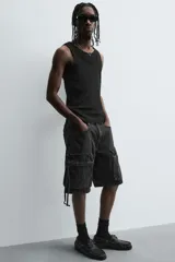 Bermuda de corte relajado en denim de algodón color beige, estilo cargo, con cinco bolsillos y bolsillos plastrón con solapa en las perneras.