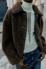 Chaqueta de cuello solapa y manga larga, con diseño de doble faz que combina tejido efecto ante y borreguillo. Cuenta con cierre frontal de botones y bolsillos delanteros.