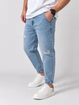 Jeans slouchy de color celeste claro, con roturas decorativas en las rodillas y botamangas con vueltita.