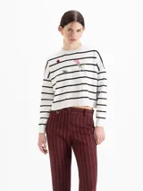 Sweater de tejido liviano color blanco con rayas horizontales negras, escote redondo, mangas largas y hombros caídos. Cuenta con pequeños bordados decorativos en el frente que representan una abeja, una flor y una frutilla.