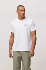 Remera de manga corta color blanco con cuello redondo y pequeño estampado cuadrado en el pecho con una cruz en color verde claro.