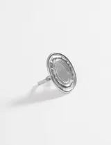 Anillo de diseño circular grande con acabado plateado y textura irregular en el borde, con banda ajustable.
