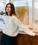 Sweater de lana merino color marfil, tejido a mano, con cuello redondo y detalles de punto trenzado y calados en V en el frente y las mangas.