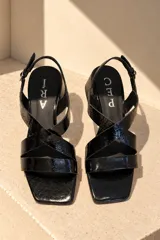 Sandalias de cuero vacuno color beige, con diseño de tiras cruzadas en el empeine, puntera cuadrada, taco bloque mediano y tira ajustable con hebilla en el talón.