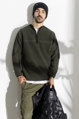 Sweater de polar verde militar con medio cierre y detalles en negro en hombros y mangas.