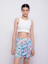 Minifalda estampada con flores en tonos celeste, azul, rosa y amarillo, con volados en el frente y cierre invisible en la parte trasera.