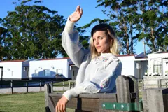 Sweater de lana merino gris con detalles bordados a mano de colores en el canesú y en las mangas. Presenta cuello redondo, volados decorativos y diseño de rombos con efecto 3D.