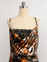 Vestido corto de seda con estampado abstracto en tonos negro, blanco y naranja. Presenta escote tipo cowl con detalle de encaje negro y breteles finos ajustables.