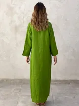 Vestido camisero largo color verde lima, con cuello camisero, mangas largas con puños abotonados, cierre frontal con botones y lazo anudado en la cintura.